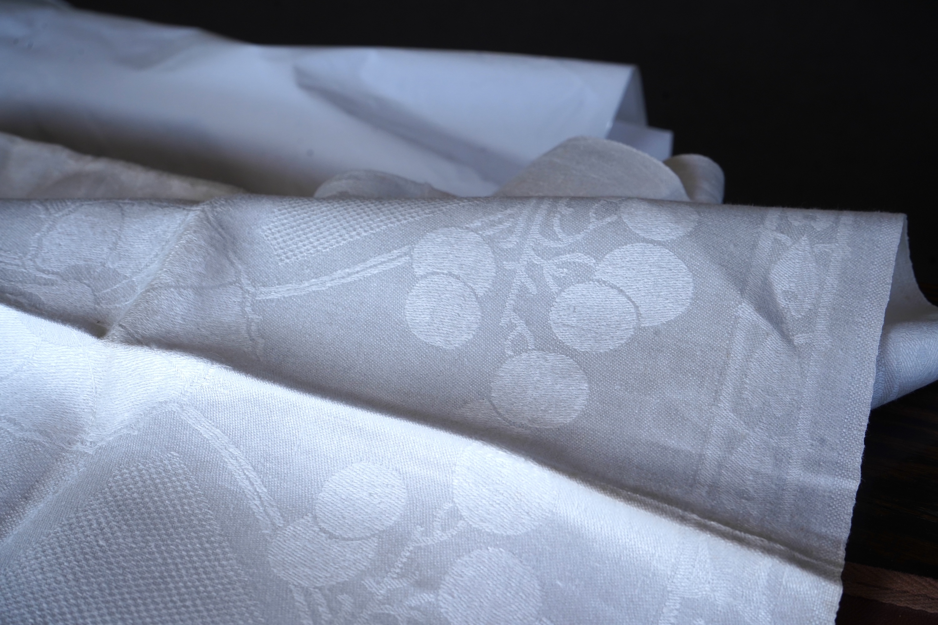 A set of four large Art Nouveau, unused white damask woven hand towels. The pattern having strong Archibald Knox and Walter Crane design elements; with trailing Honesty seeds and Tulip flower heads, these motifs much use